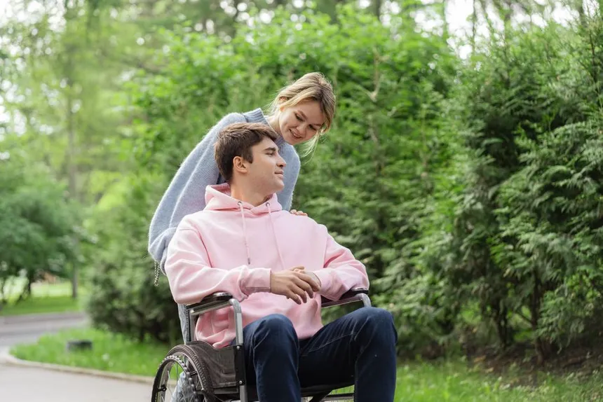 A support worker walking with a man using a wheelchair
