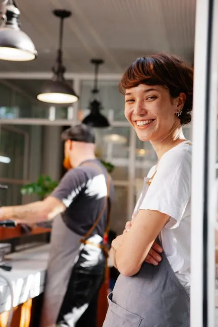 A young adult smiling in a sunlit doorway