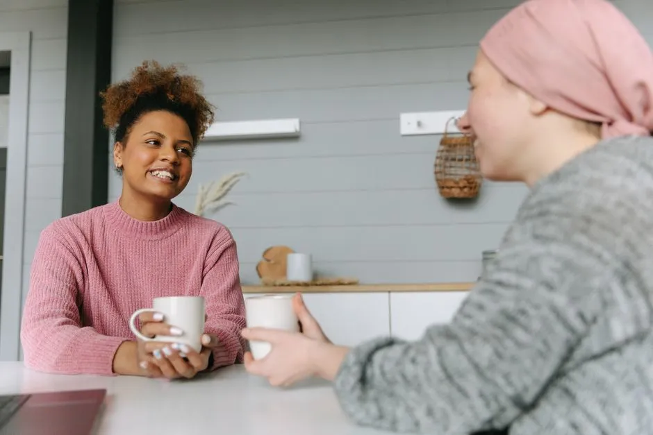 A support worker and a parent talking at a kitchen bench