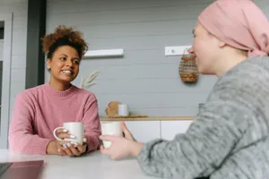 Two women sharing a coffee and a conversation at a kitchen bench