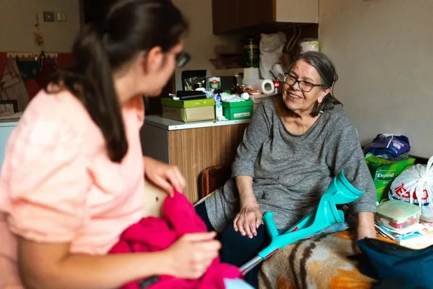 A support worker sitting and chatting with an older woman in her living room