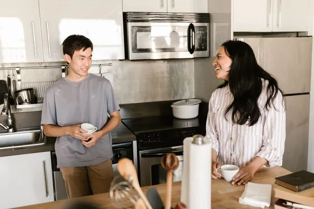 Two housemates chatting over coffee in a shared kitchen