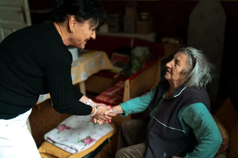 An older person's hands held gently by a support worker